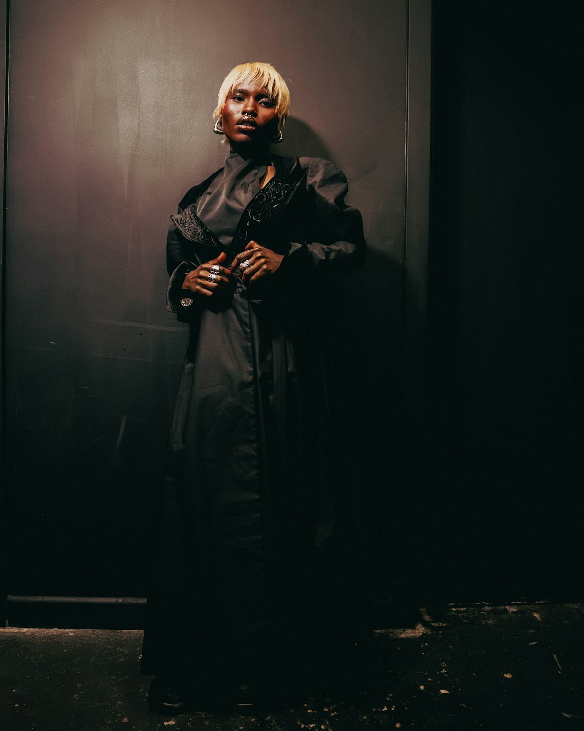 Editorial figure in a black coat under dramatic side light